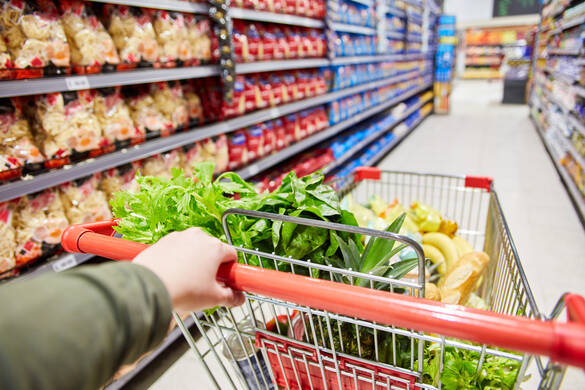 Le client pousse le chariot avec la nourriture par un couloir dans le supermarché