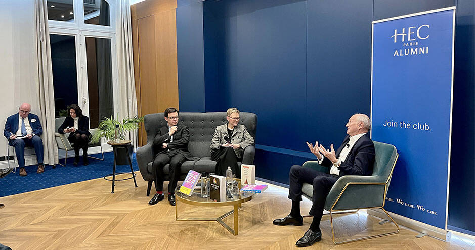 Jean-Paul Agon lors d'une table ronde à la Maison des Alumni HEC Paris, assis dans un fauteuil vert face à un public dans une salle aux murs bleus.